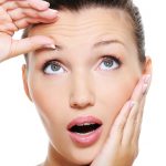 young pretty woman squeeze skin on forehead